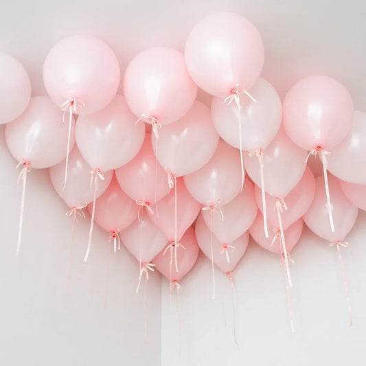 Baby pink ceiling balloons with ribbons in a white room, party decoration Dubai