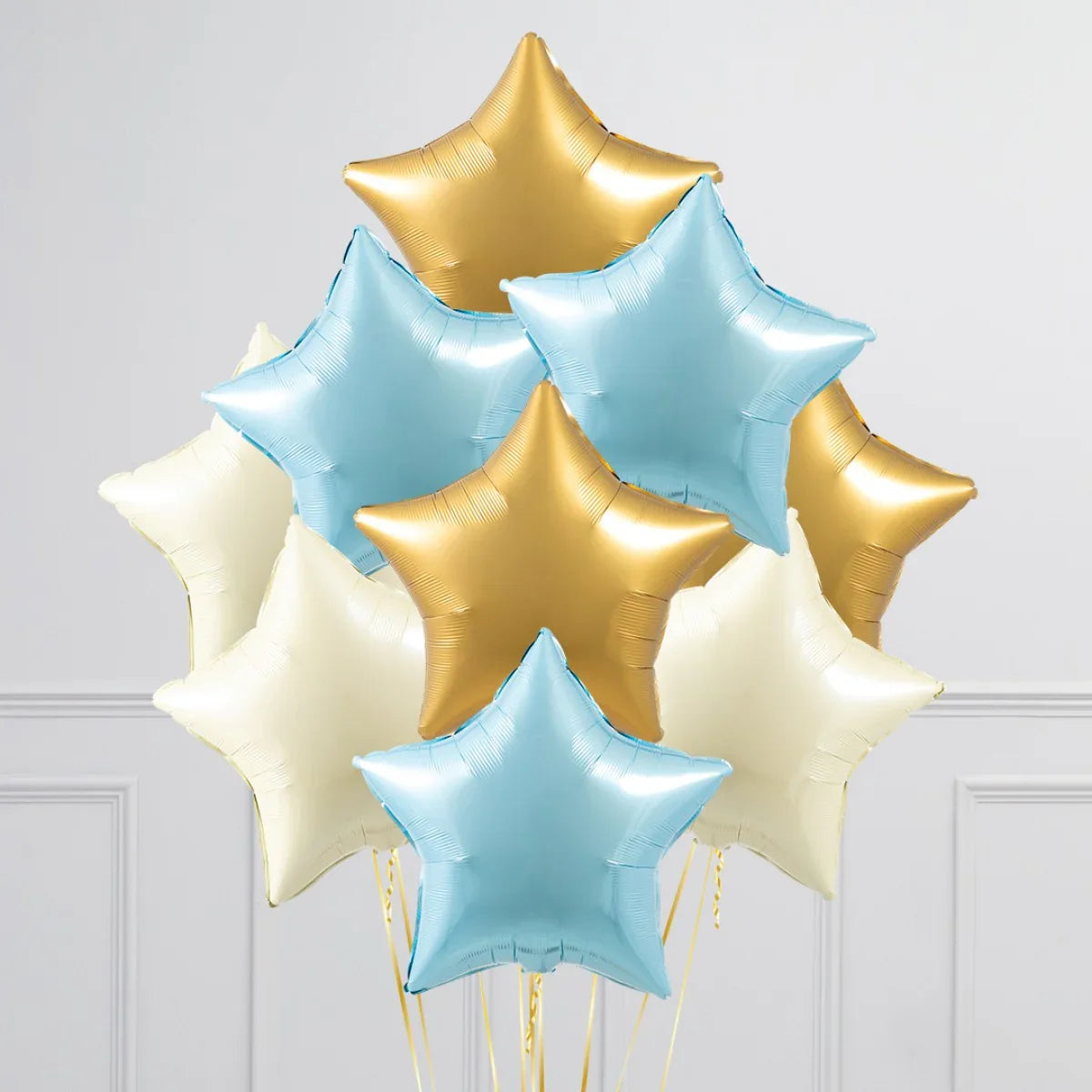 Cluster of baby blue, gold, and cream star-shaped foil balloons against white wall