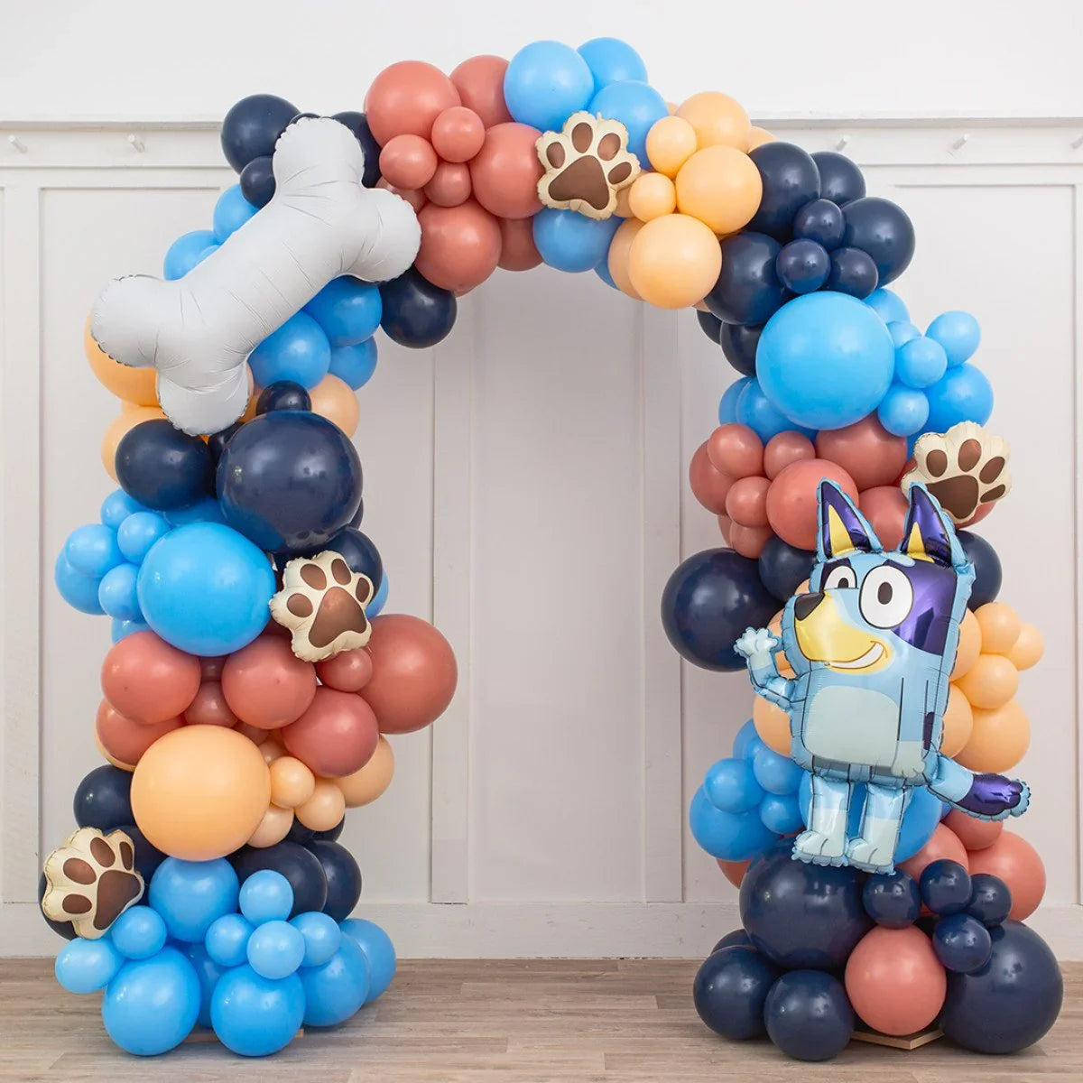 Colorful balloon arch with bluey cartoon character, paw prints, and dog bone balloons for party decor
