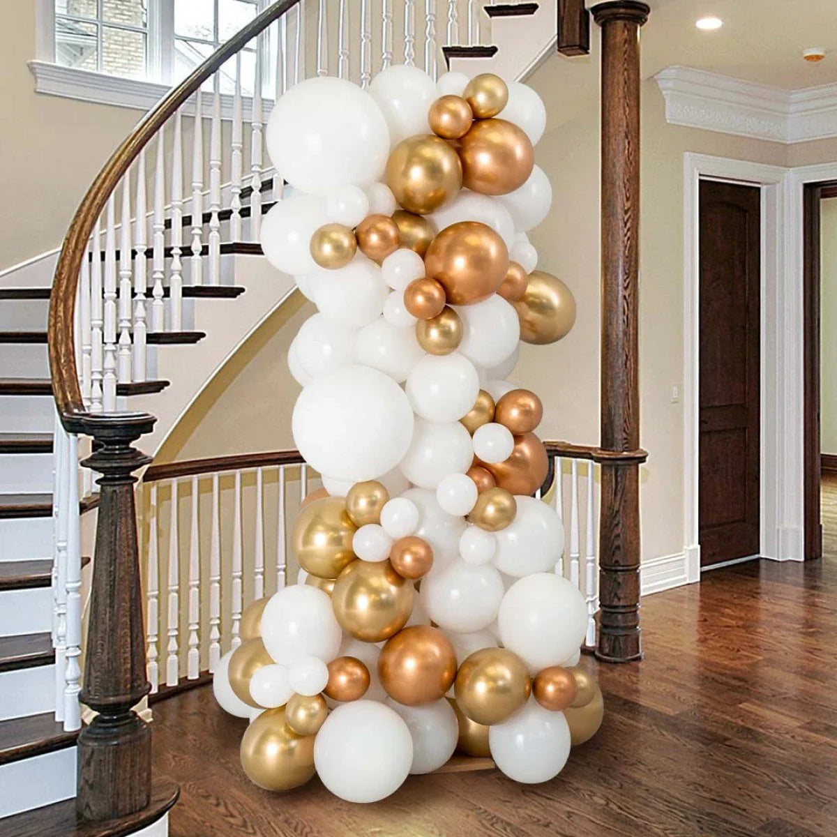 Decorative balloon pillar with white, copper, and gold balloons in a modern home entrance with wooden stairs