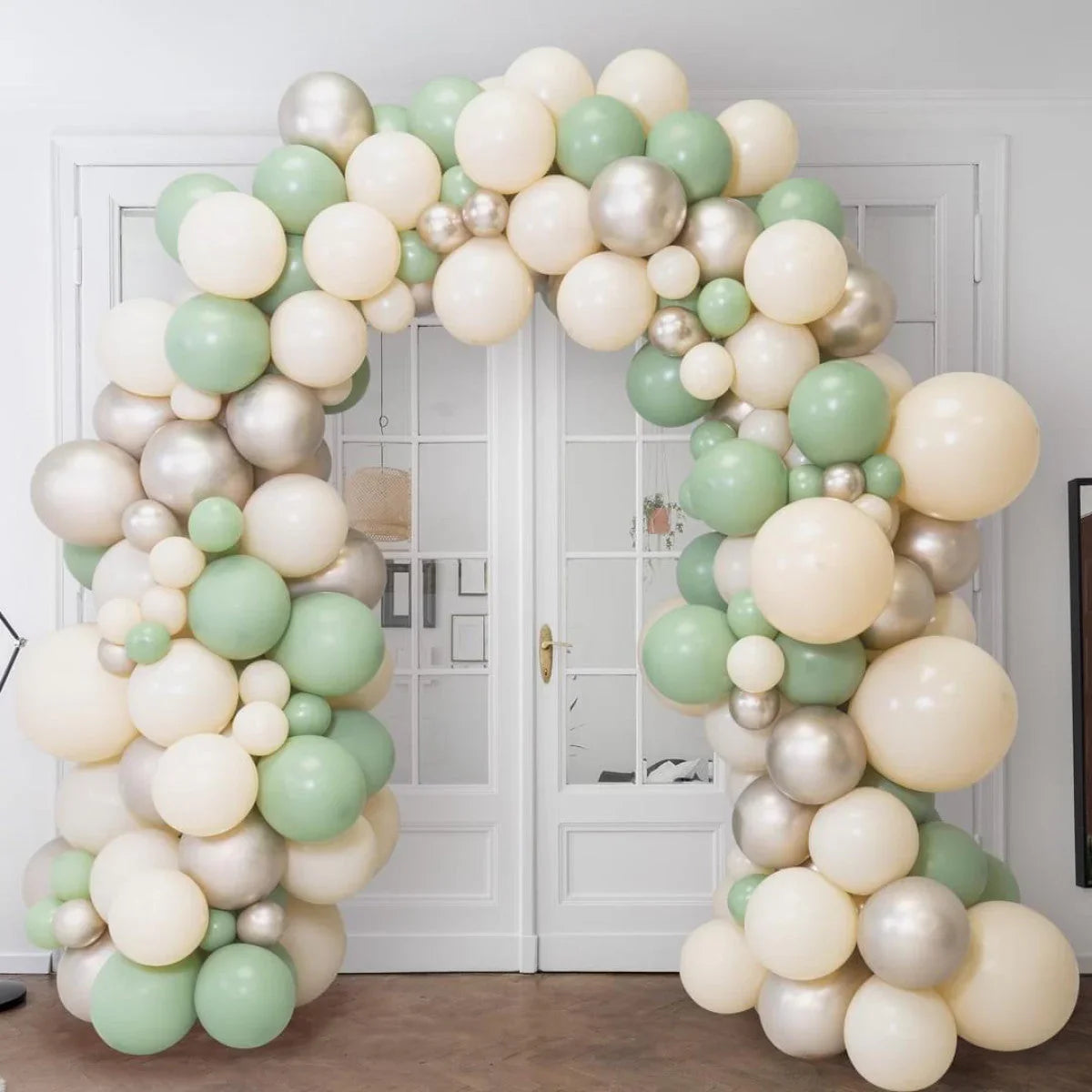 Cream green silver helium balloon arch decoration in front of glass doors indoors