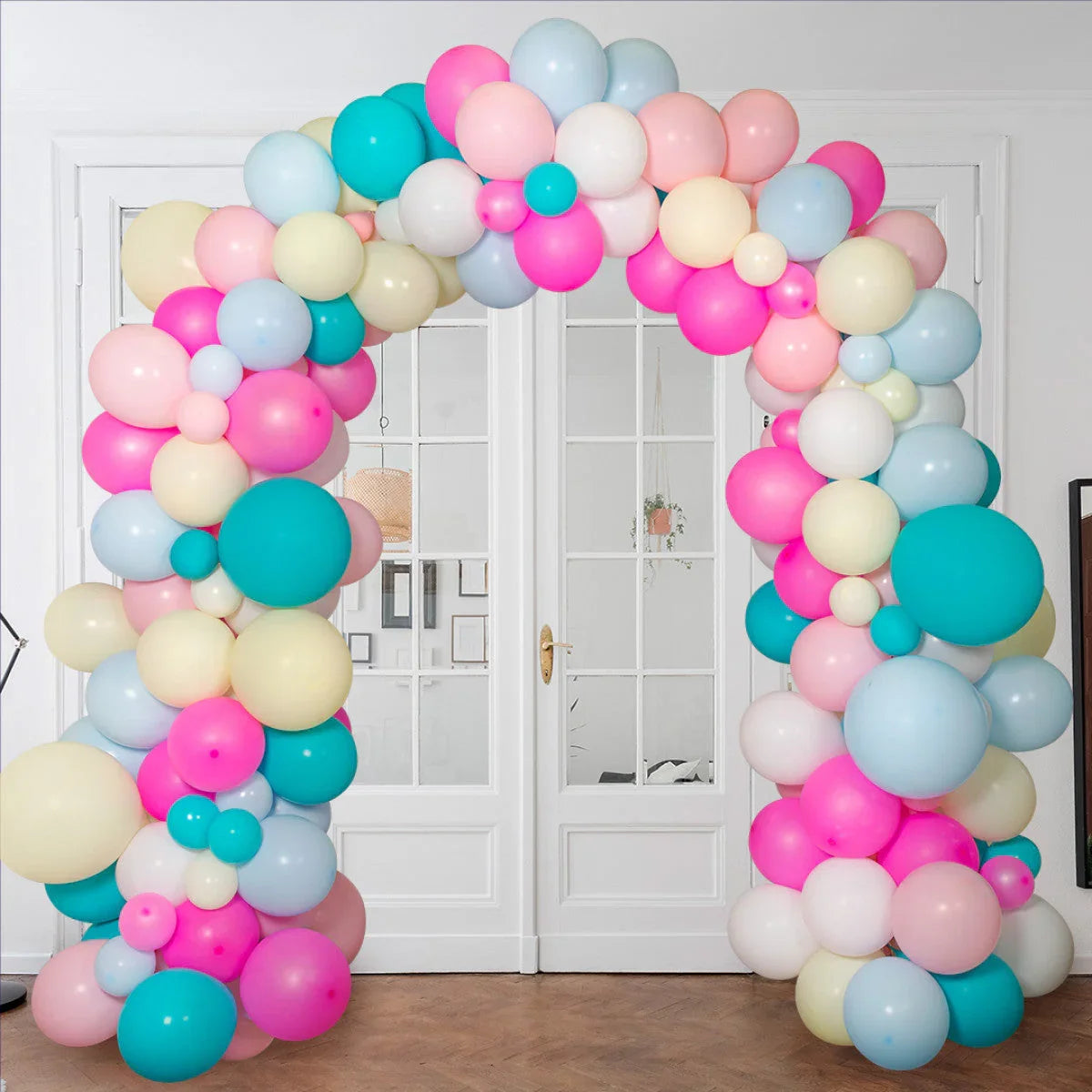 Colorful balloon arch with pink, blue, white, and cream balloons in front of white double doors