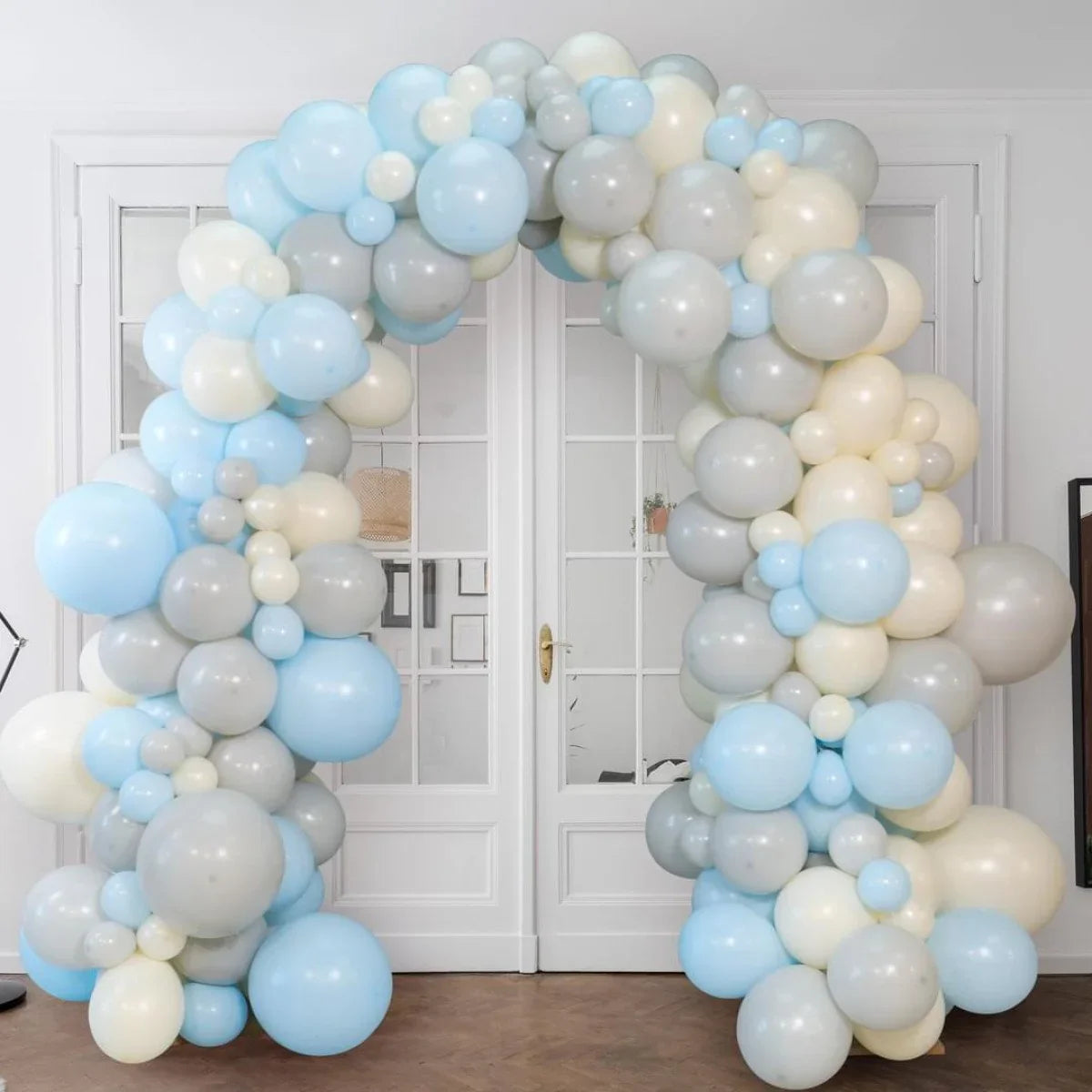 Pastel blue, grey, and cream balloon arch decor in front of white double doors in Dubai