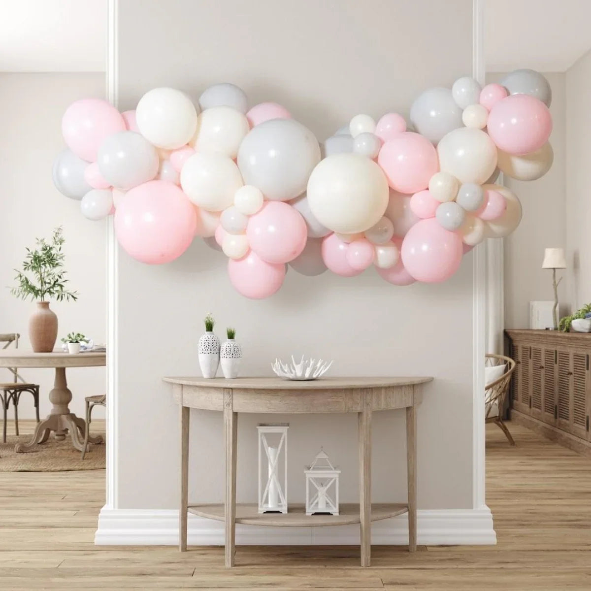 Pink, white, and gray balloon macaron garland decoration above rustic wooden console table in modern neutral room