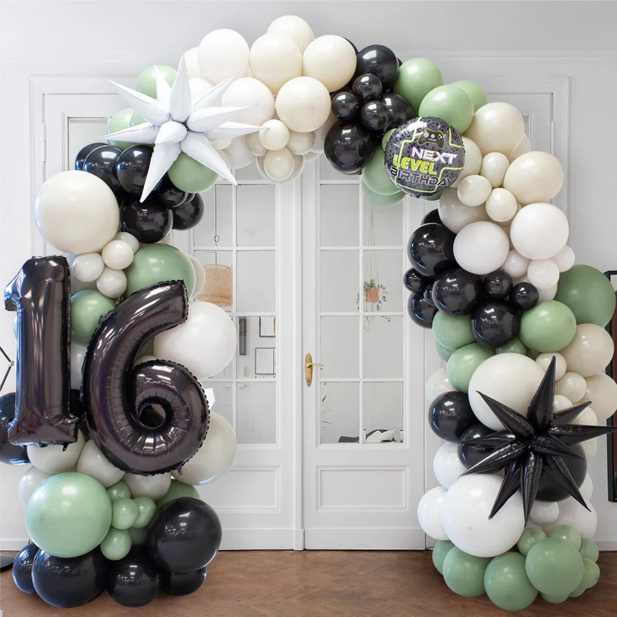 Birthday balloon arch with black, white, and green balloons, featuring large 16 and star-shaped balloons
