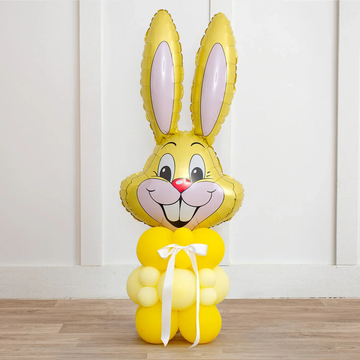 Yellow Easter bunny balloon sculpture with inflated face and body balloons tied with white ribbon