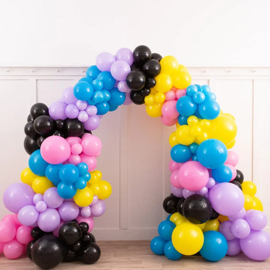 Colorful balloon arch with pink, yellow, blue, black, and purple balloons indoors in Dubai
