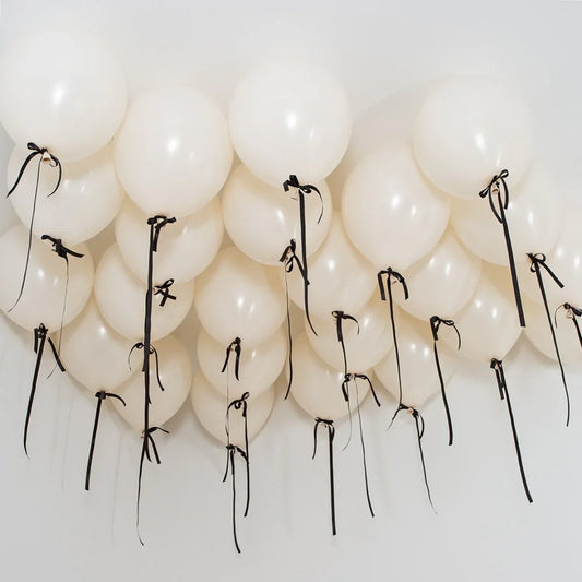 Ivory helium ceiling balloons with black ribbons in a white Dubai room
