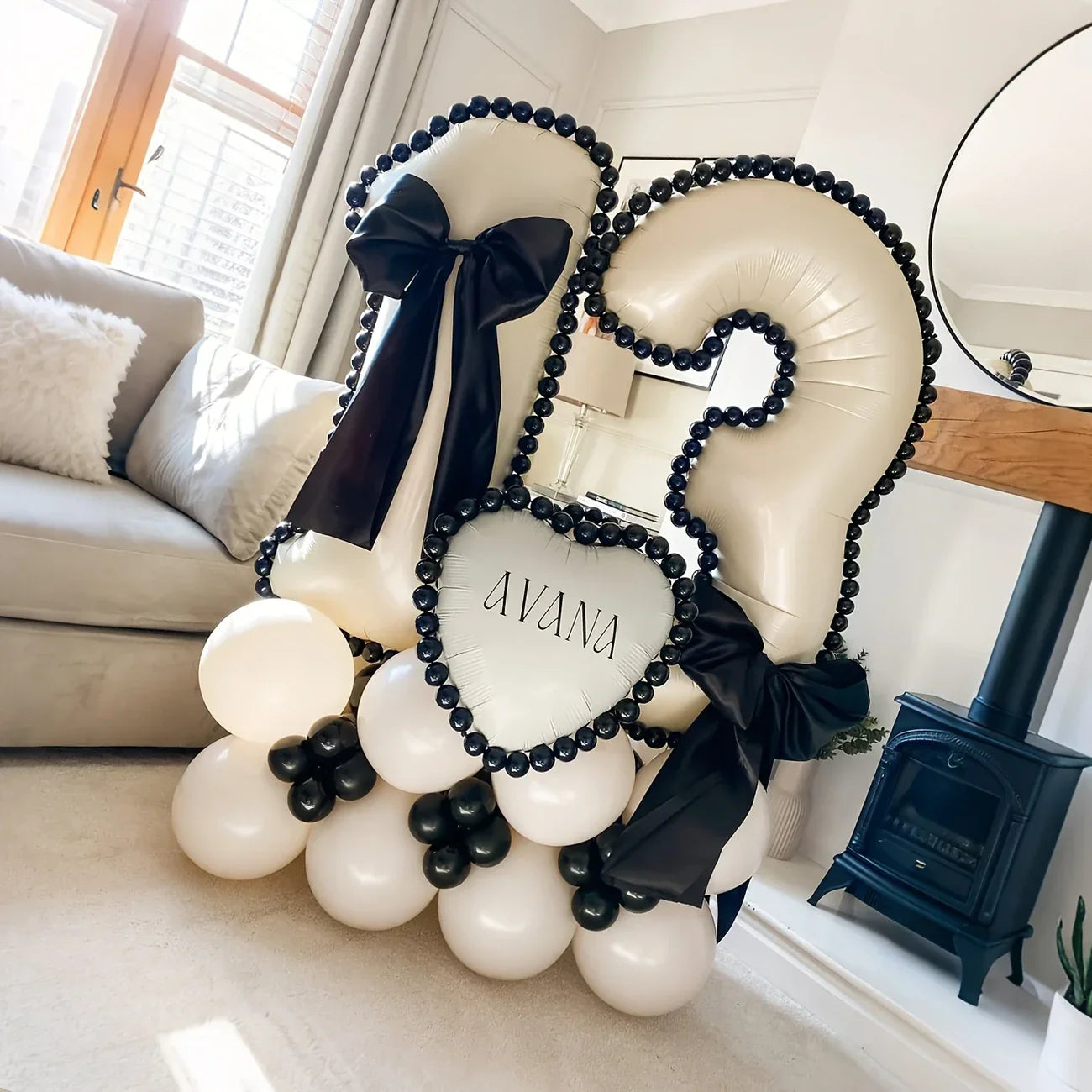 White number 12 balloon arrangement with black bows and black bead trim on beige balloons in living room
