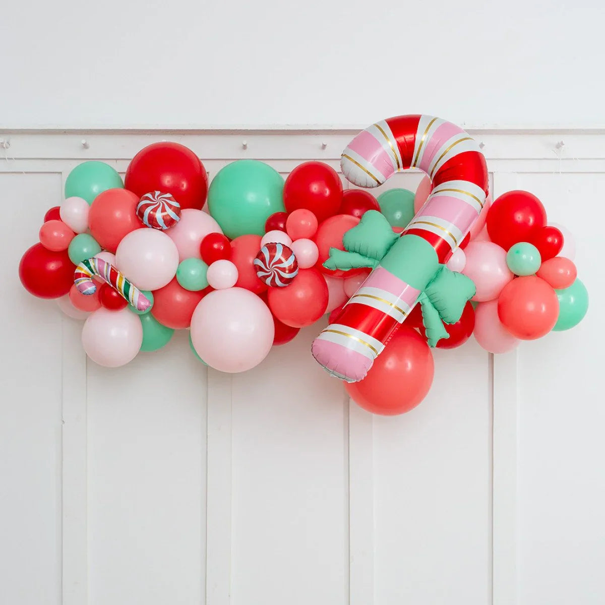Festive Christmas balloon garland with red, pink, green balloons and candy cane foil balloon