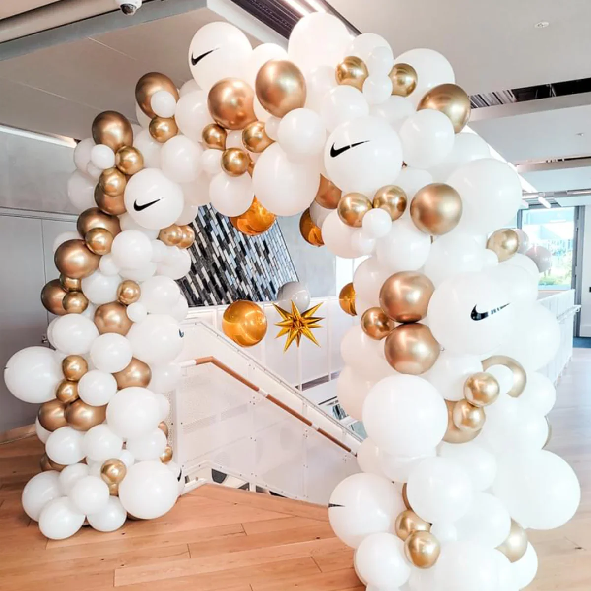 White and gold balloon arch with Nike logos in modern indoor space