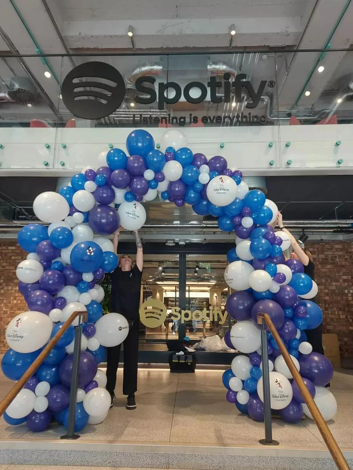 Blue, purple, and white balloon arch with Walt Disney logos at Spotify office entrance