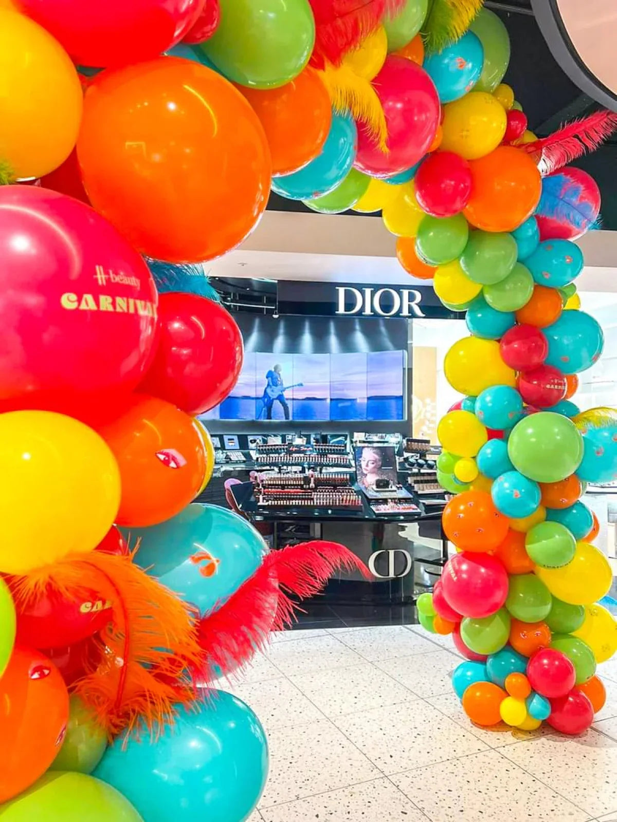 Colorful balloon arch with feathers at luxury Dior cosmetics store entrance in a mall