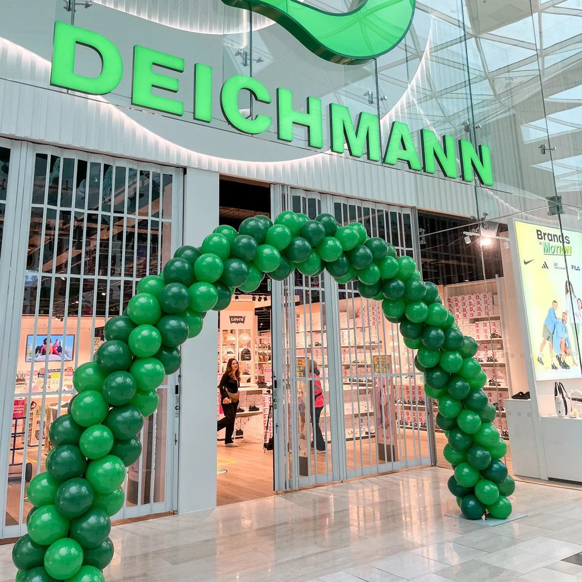 Green balloon arch at Deichmann shoe store entrance inside shopping mall