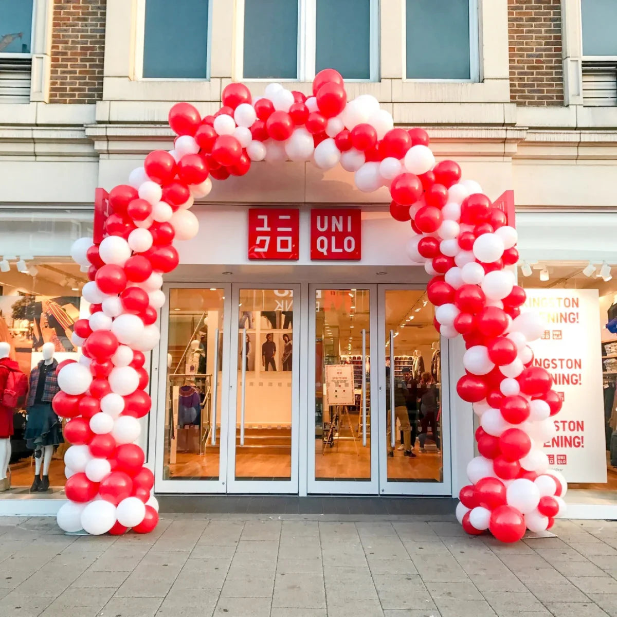 Red and white balloon arch at entrance of UNIQLO store during grand opening event
