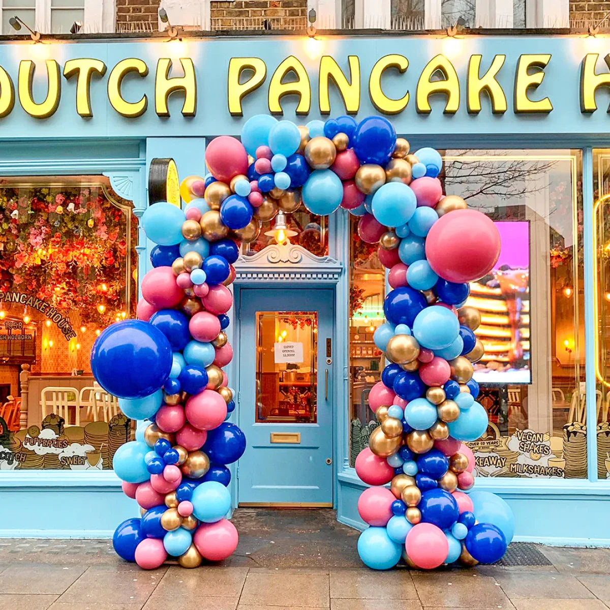 Colorful balloon arch in blue, pink, and gold at Dutch Pancake House entrance