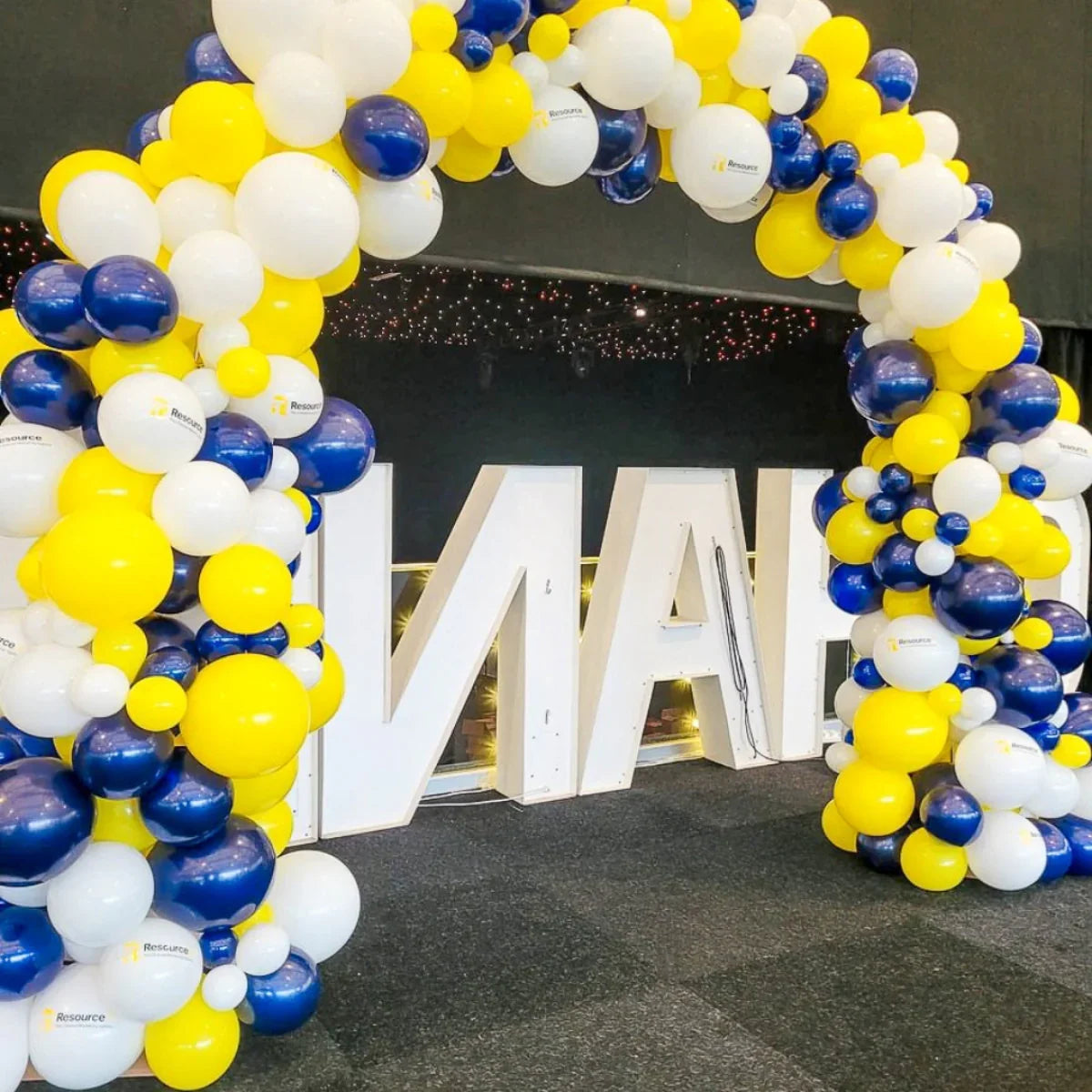 Yellow, white, and blue corporate balloon arch with Resource logo balloons at event venue