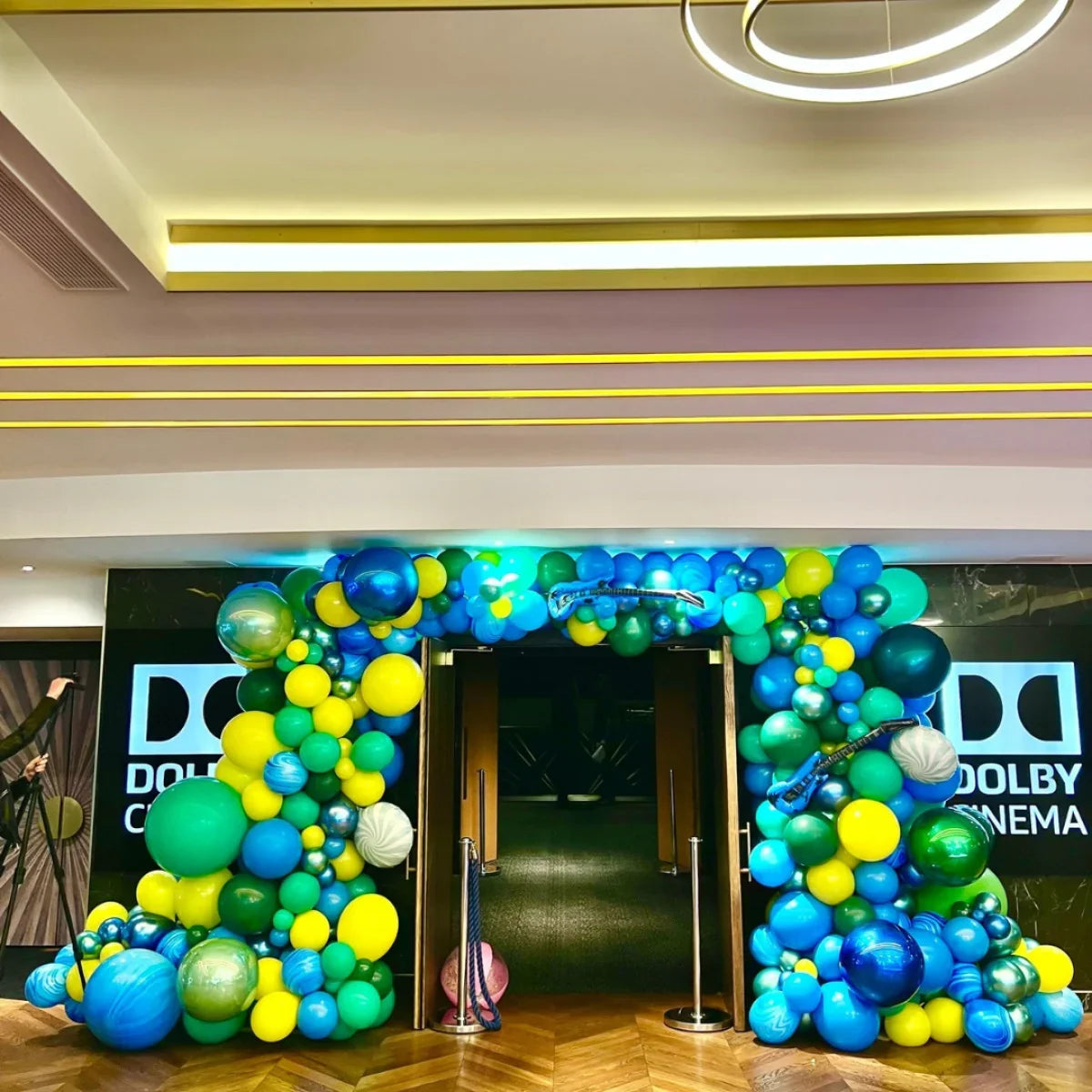 Colorful balloon arch in blue, green, and yellow at Dolby Cinema entrance for event decoration