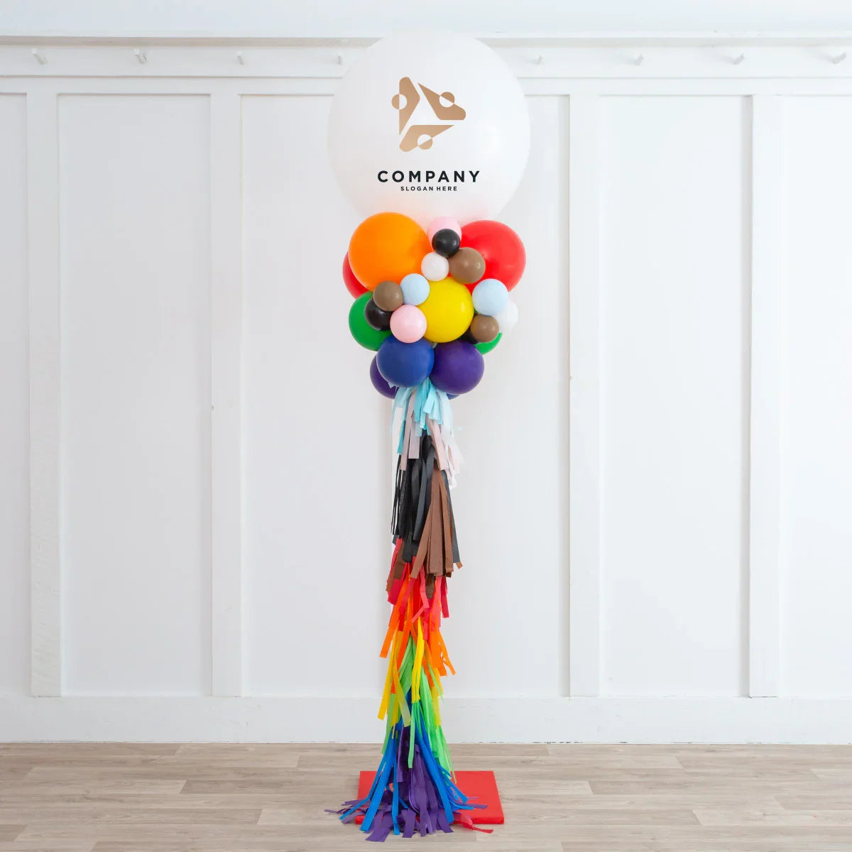 Corporate balloon party pillar with colorful balloons and tassels, white wall and wooden floor background