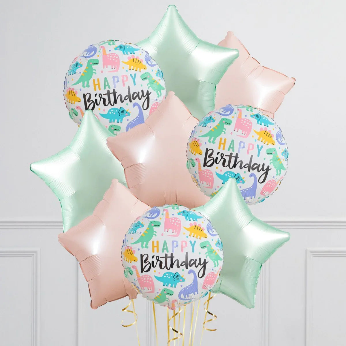 Colorful dinosaur-themed happy birthday foil balloons with pastel pink and mint star-shaped balloons