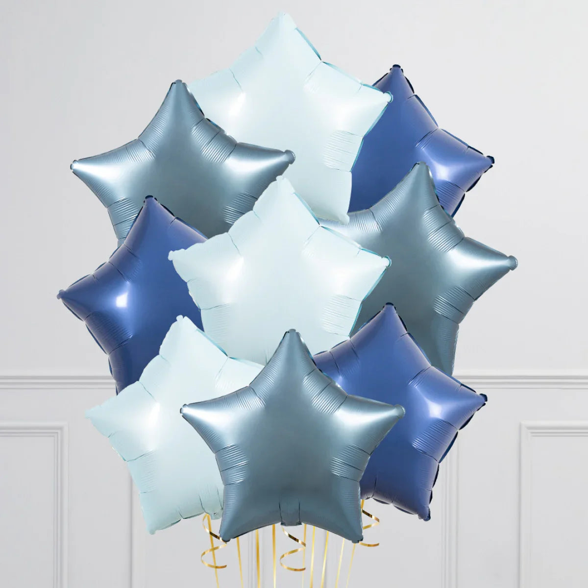 Bunch of blue and silver star-shaped foil balloons against white wall with molding