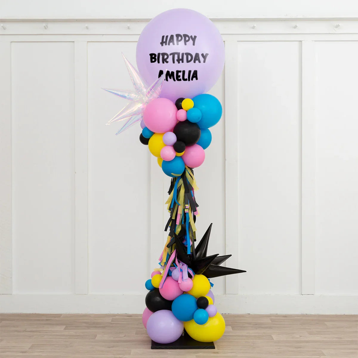 Colorful birthday balloon pillar with pink, blue, yellow, black balloons and star-shaped balloons