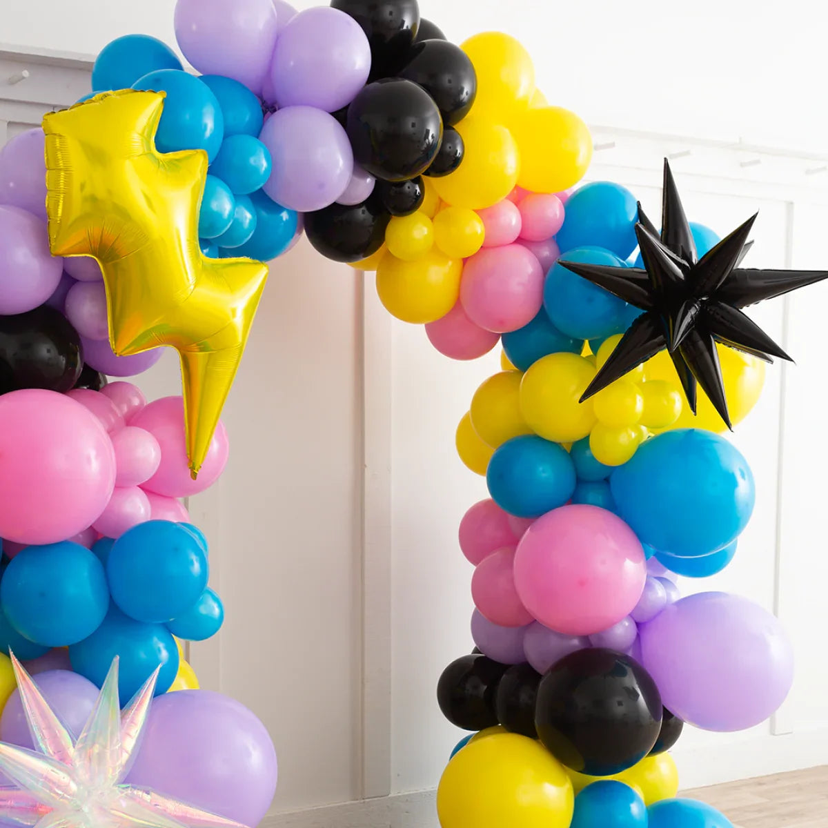 Colorful balloon arch with yellow lightning bolt and black star foil balloons in a bright room