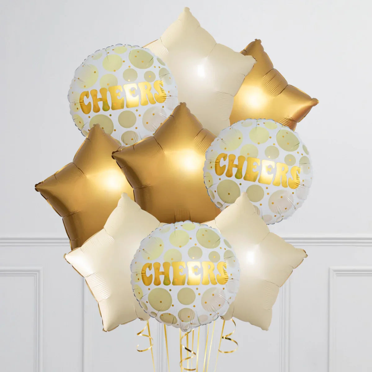 Gold and cream star-shaped and round foil balloons with Cheers text in a neutral indoor setting