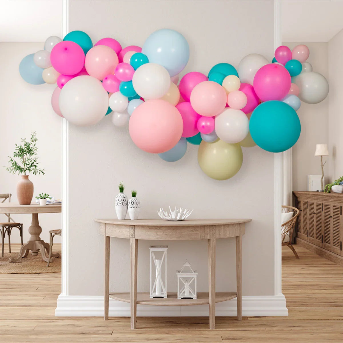 Colorful balloon garland with pink, blue, white, and green balloons above wooden console table in cozy living room