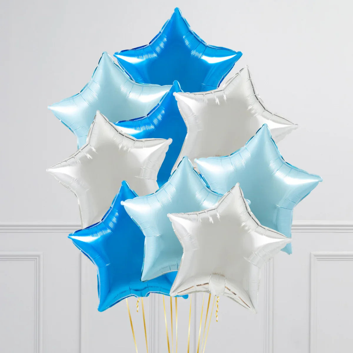 Bunch of inflated star-shaped foil balloons in blue, light blue, and silver against white wall