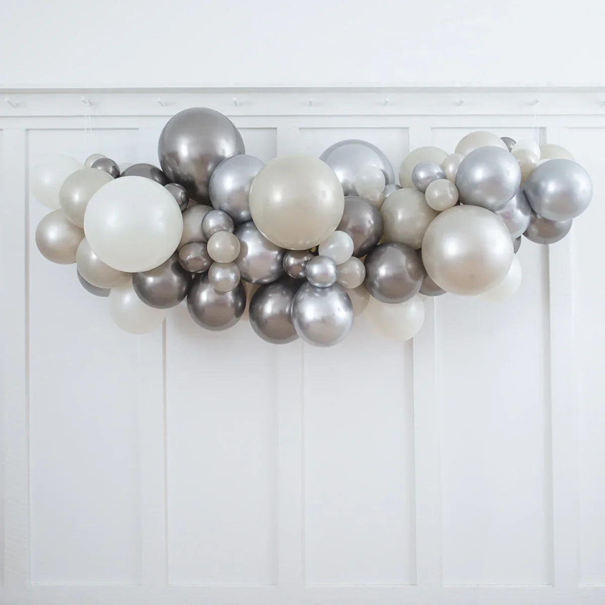 Silver and pearl white balloon garland decoration on white paneled wall for events