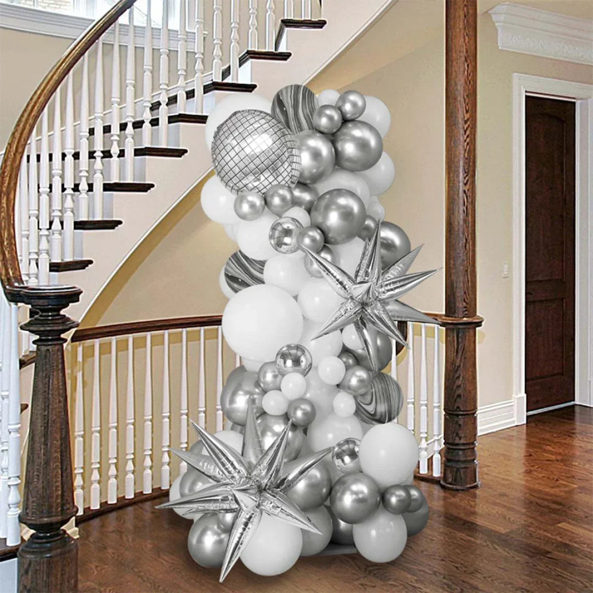 Silver and white inflated balloon pillar with star shapes in a wooden staircase hallway