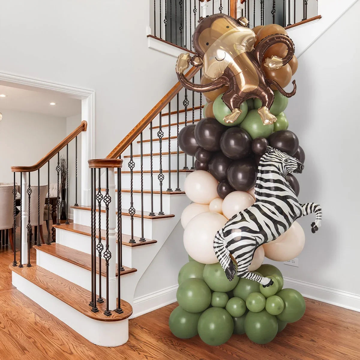 Jungle-themed balloon pillar with inflatable monkey and zebra near indoor staircase