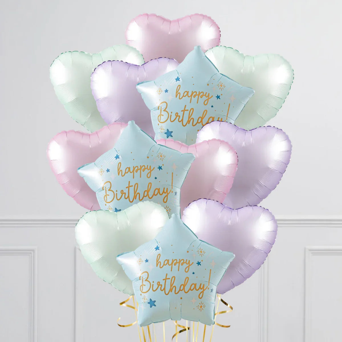 Pastel heart-shaped and star-shaped happy birthday foil balloons arranged in a bunch indoors
