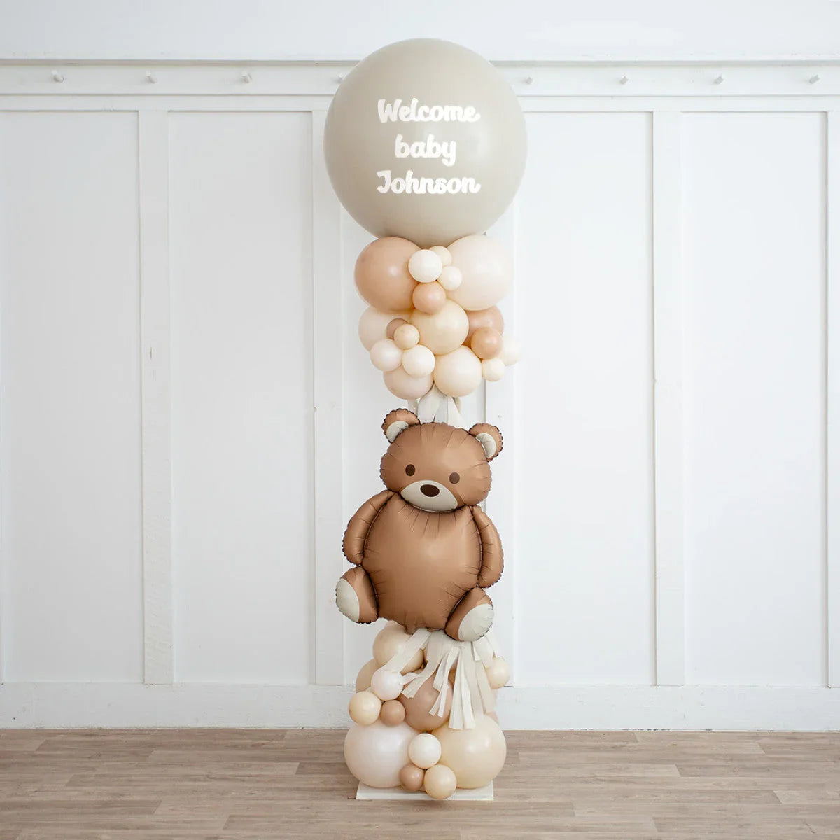 Neutral beige balloon pillar with teddy bear and welcome baby Johnson text for gender reveal party