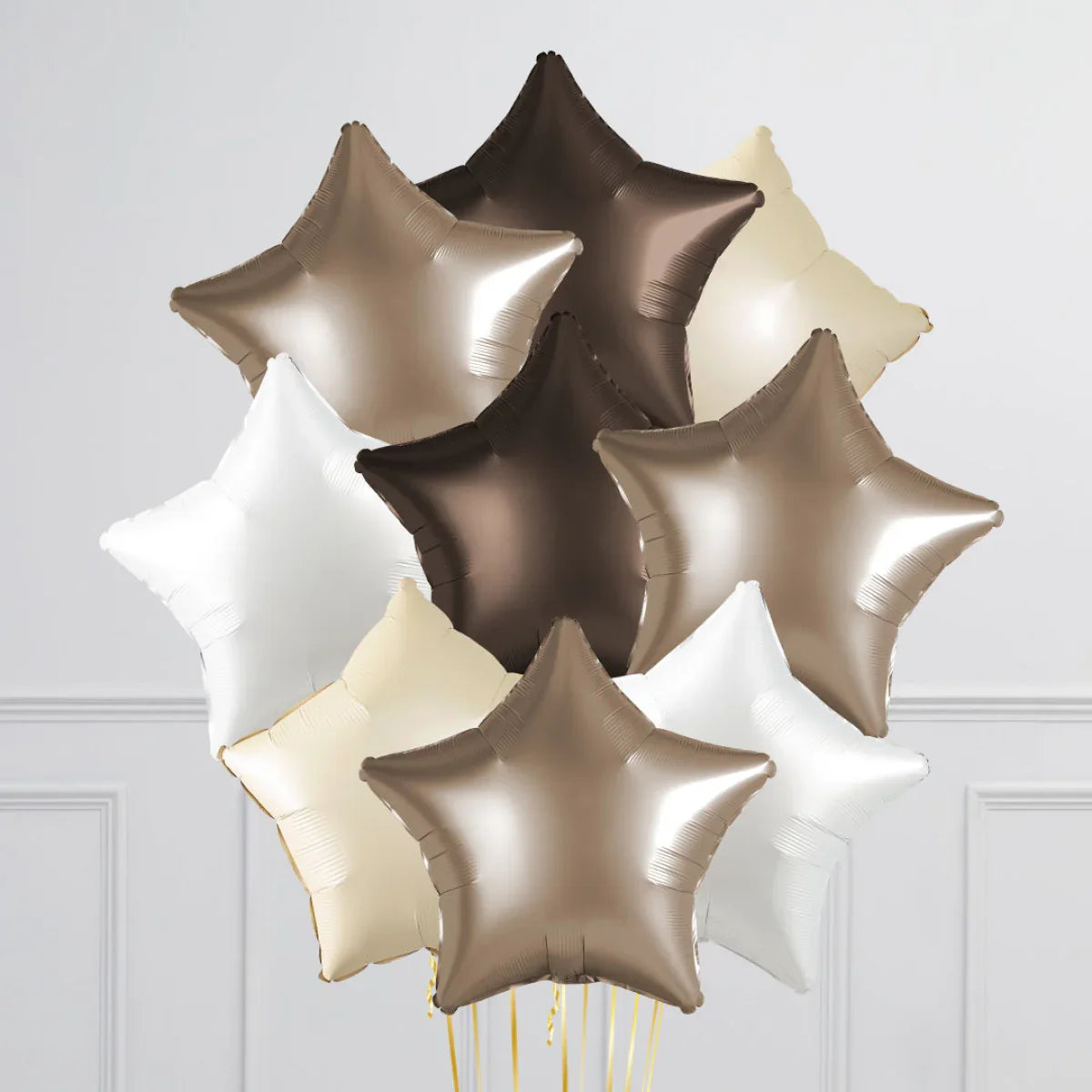 Neutral toned star-shaped foil balloons in silver, gold, cream, and white colors on a white background
