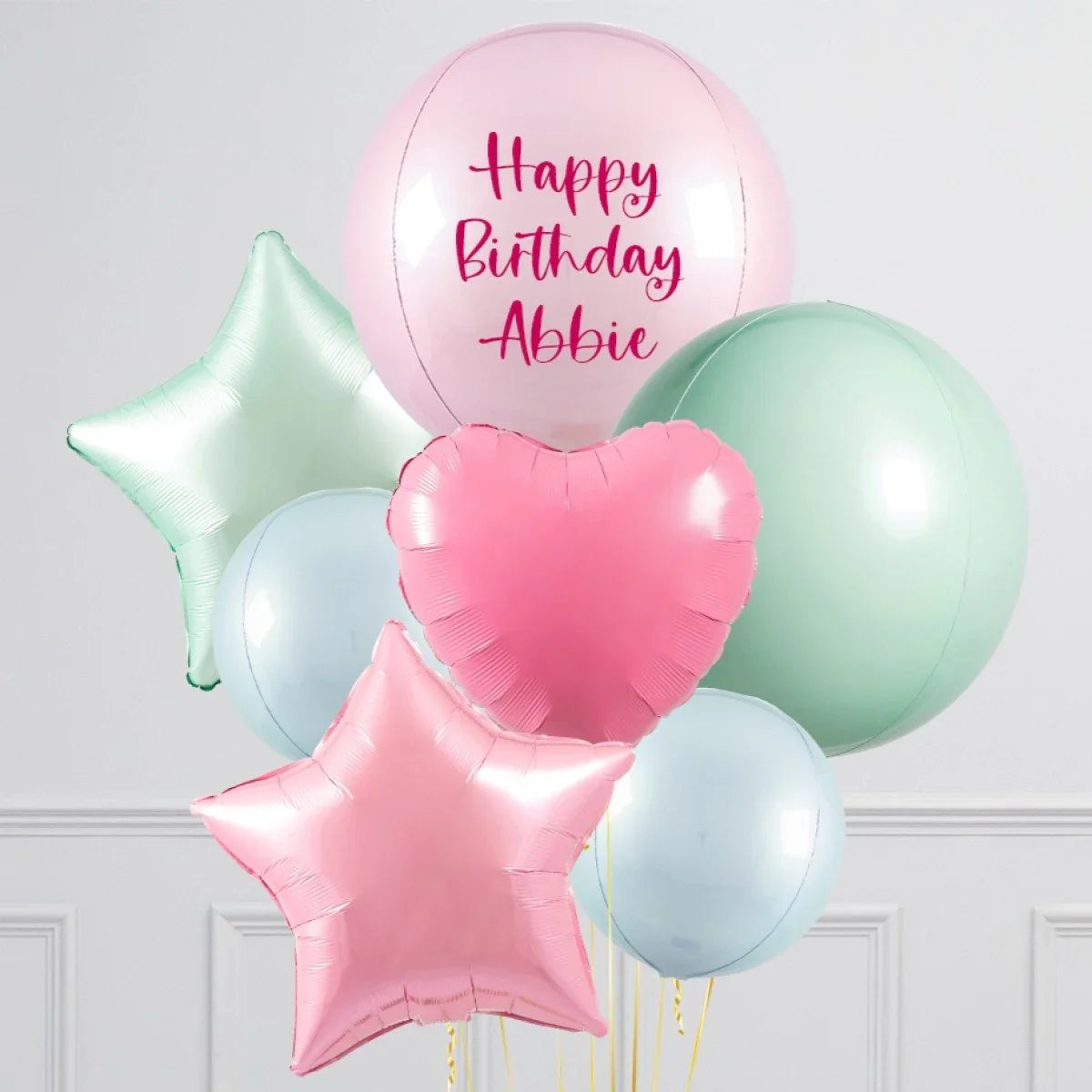 Pastel colored helium balloons including pink heart, stars, blue and green round balloons with Happy Birthday Abbie text