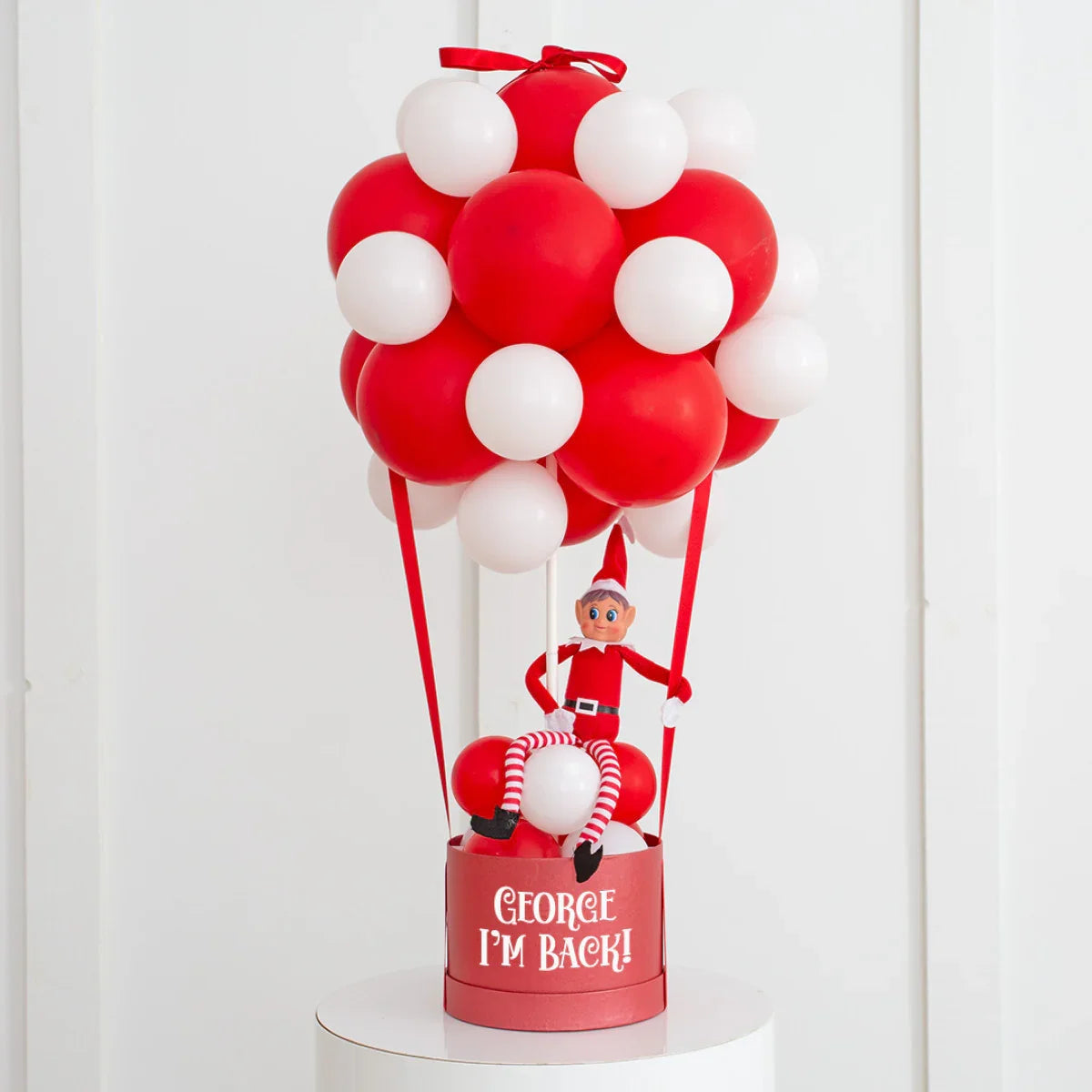 Red and white balloon hot air balloon decoration with elf doll and text George I'm Back on basket