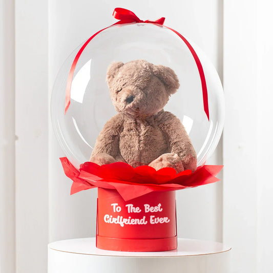 Romantic brown teddy bear gift in a bubble with red ribbon and 'To The Best Girlfriend Ever' text.