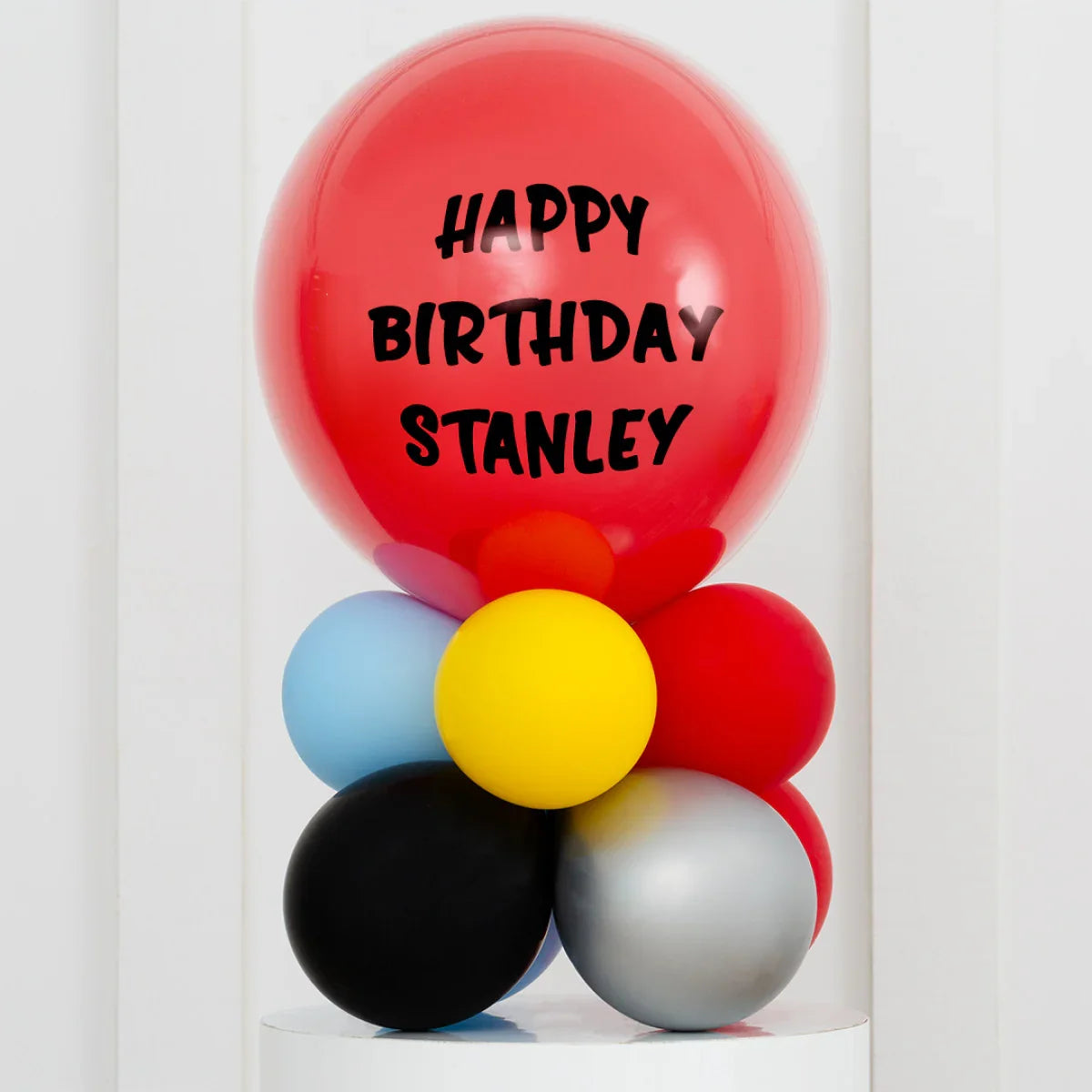 Personalized superhero-themed birthday balloon stack with 'Happy Birthday Stanley' text in Dubai