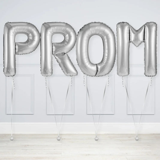 Silver PROM letter balloons against a white wall, prom decoration Dubai