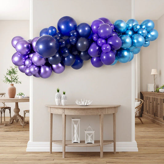 Indoor metallic blue and purple balloon garland hanging above wooden console table in modern living space
