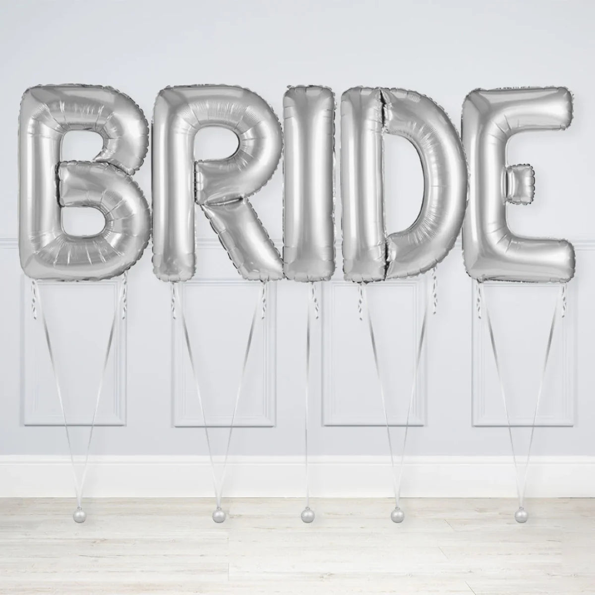 Silver inflated balloons spelling BRIDE against a white wall and wooden floor