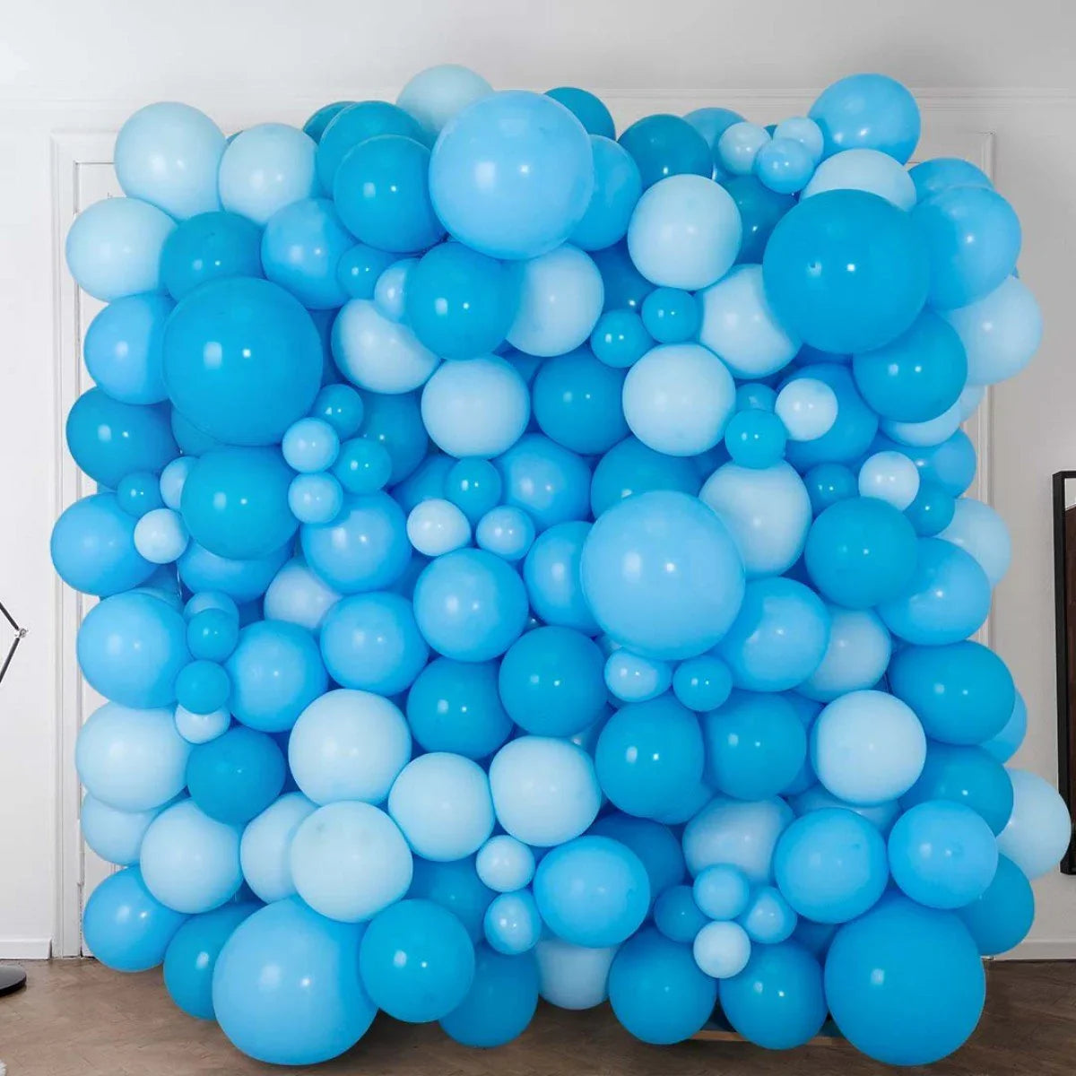 Decorative balloon wall made of varying shades of blue balloons in an indoor setting