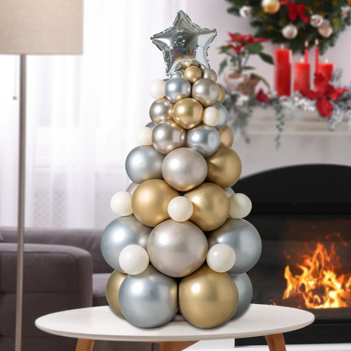 Gold and silver balloon Christmas tree with star topper on white table by fireplace
