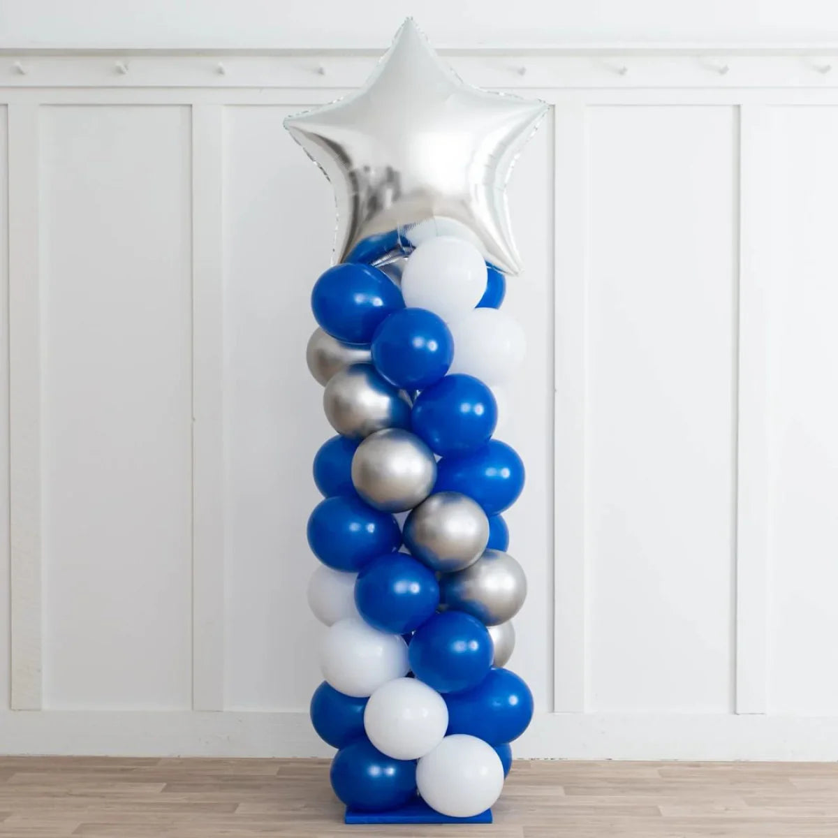 Spiral balloon pillar with blue, white, and silver balloons topped with a large silver star balloon