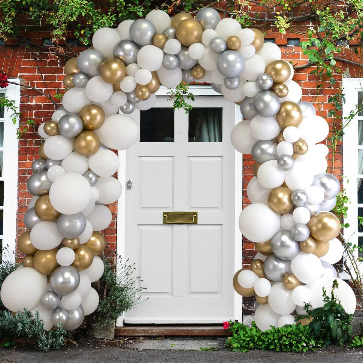 White door decorated with a stylish metallic balloon arch in gold, silver, and white outdoors