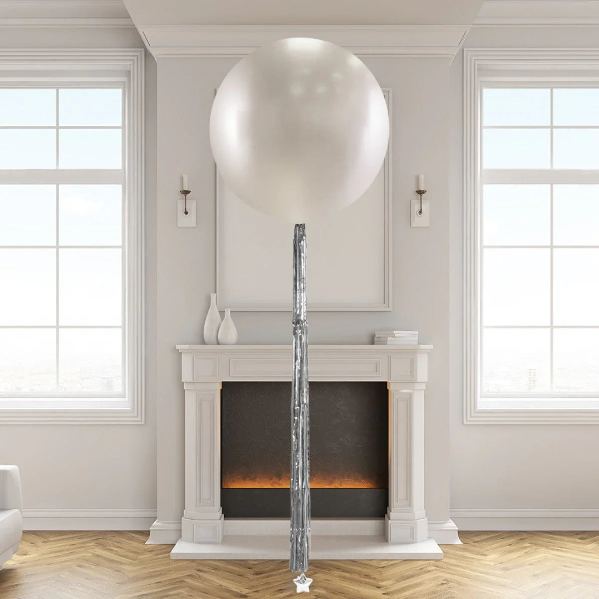 Large metallic silver helium balloon with silver tassel tail in a bright living room with fireplace