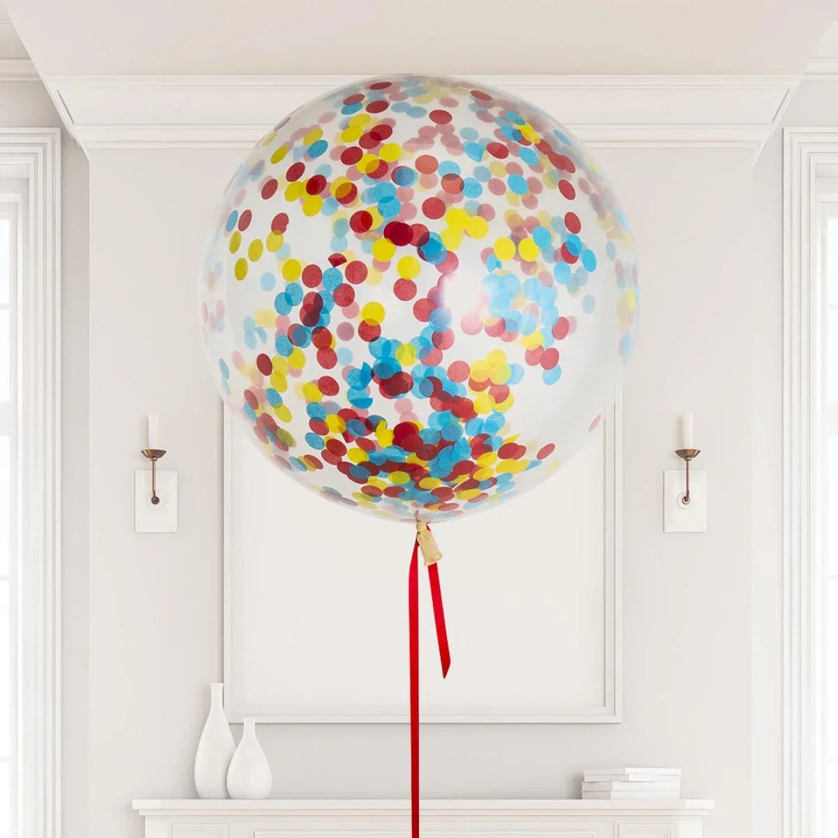Large transparent helium balloon filled with colorful red, blue, and yellow confetti in elegant white room