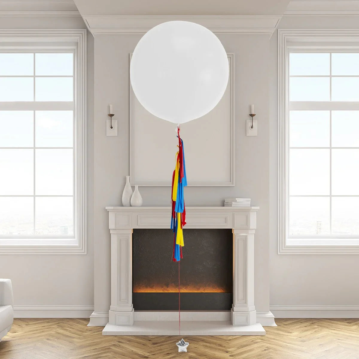 Large white helium balloon with red, yellow, and blue tassels floating in a bright living room above a white fireplace